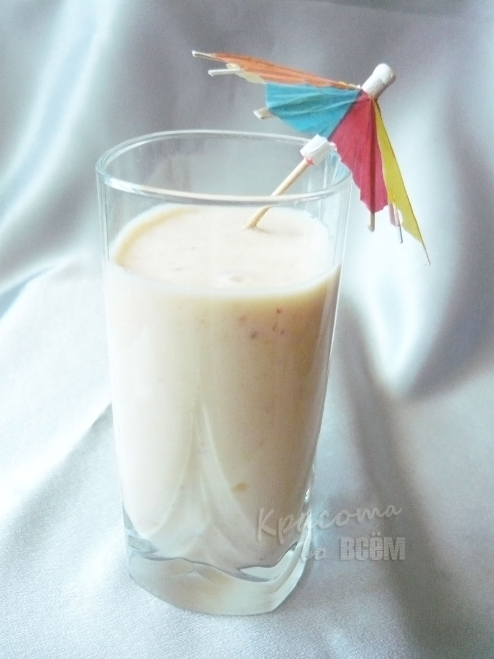 Летний рецепт смузи из фруктов в стакане с декоративным зонтиком.